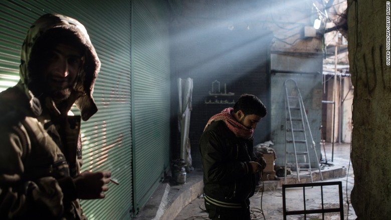 A rebel fighter prepares the wires of a car-mounted camera used to spy on Syrian government forces while his comrade smokes a cigarette in Aleppo&#39;s Bab al-Nasr district on January 7, 2013.