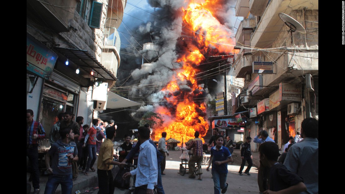Residents run from a fire at a gasoline and oil shop in Aleppo&#39;s Bustan Al-Qasr neighborhood on October 20, 2013. Witnesses said the fire was caused by a bullet from a pro-government sniper.