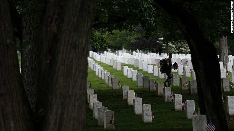 Members of the 3rd U.S. Infantry Regiment place American flags at the foot of graves in Arlington National Cemetery on Thursday, May 21.