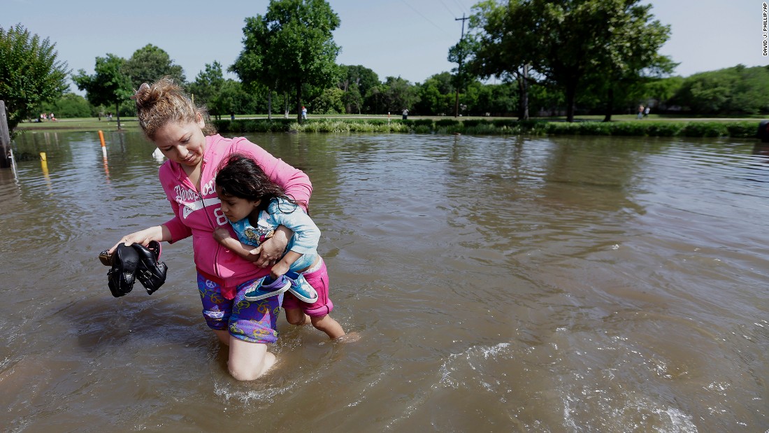 Nayeli Cervantes carries her friend&#39;s daughter through the floodwaters outside their Houston apartment on May 26.