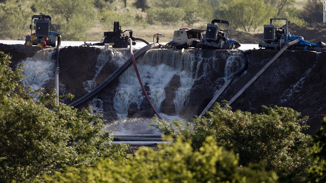 Workers in Midlothian, Texas, try to relieve pressure from the dam at Padera Lake on Wednesday, May 27. Water was flowing over the top of the dam following days of heavy rain. Record-setting rains and dangerous storms have been battering Texas and Oklahoma since Memorial Day weekend.