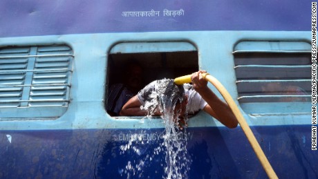 A commuter uses a train's hose pipe to cool down at the railway station in Allahabad on Sunday, May 24.