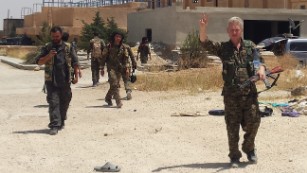 In this handout photo provided by Kurdish journalist Mohammed Hassan, taken on May 19, 2015, Michael Enright, right foreground, a British actor who has had minor roles in Hollywood films, wears the Kurdish fighters military uniform and flashes the victory sign after he joined them battling against the Islamic State group, near Tel Tamr town, northeast Syria. Enright, who played a deckhand in &quot;Pirates of the Caribbean: Dead Man&#39;s Chest,&quot; appears in a video released by the Kurdish People&#39;s Protection Units, known as the YPG. The video shows him in a trench with other fighters firing an assault rifle. (Mohammed Hassan via AP )