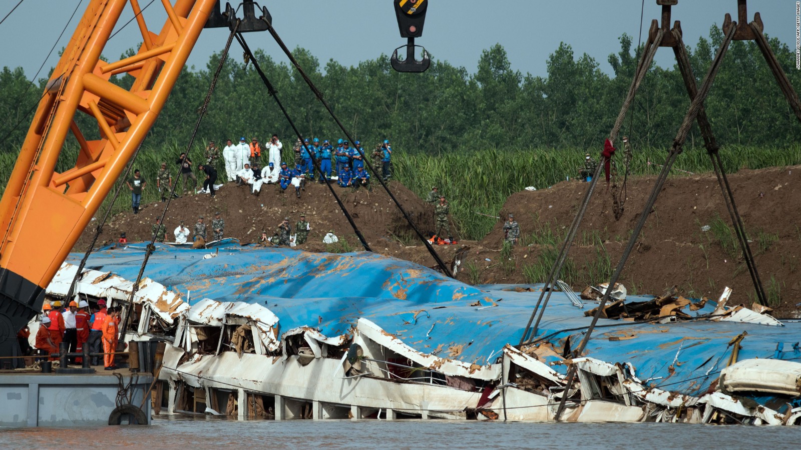 Rescue workers look at the sunken passenger ship being lifted by cranes in the Yangtze river in Jianli in China's Hubei province on June 5, 2015. Relatives of passengers missing after a Chinese cruise ship capsized expressed agony and anger after an official admitted there is no hope of finding more survivors.