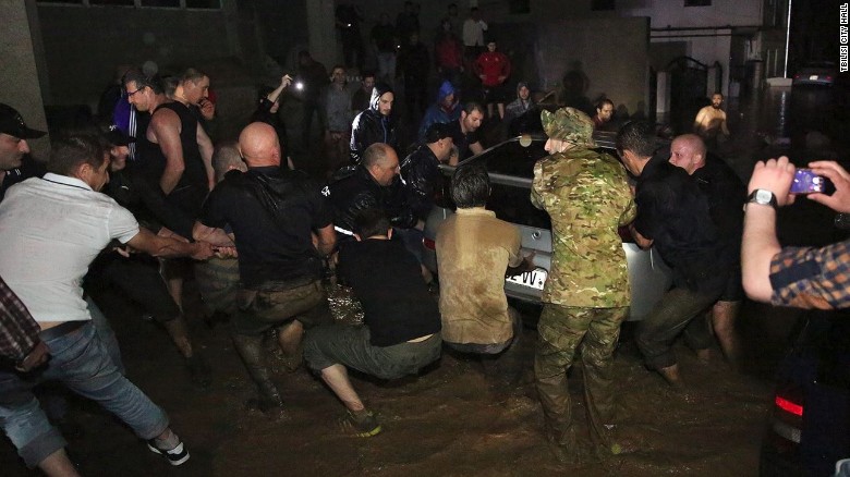 Residents join together to try to pull a car from flood waters in Tbilisi, Georgia.