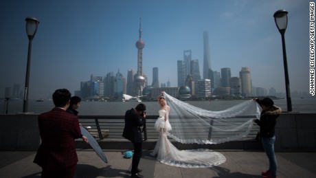 A woman poses for a wedding picture at the Bund in front of the financial district of Pudong in Shanghai on a sunny day on March 19, 2015. 