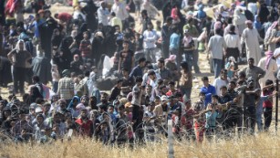 Syrians fleeing fighting in Tal Abyad, Syria, seek water at a crossing on the Syrian side of the Turkish border. 