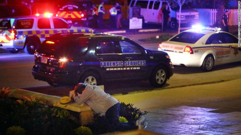 A man kneels across the street from where police gather outside the Emanuel African Methodist Episcopal Church after a shooting on Wednesday, June 17, in downtown Charleston, South Carolina.