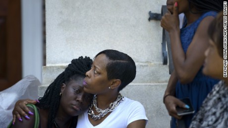 People sit on the steps of Morris Brown AME Church in Charleston while services are held June 18. 