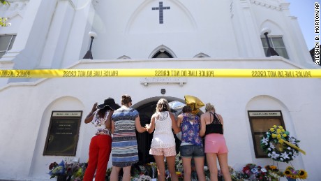 A group of women prays together at a makeshift memorial on the sidewalk in front of the Emanuel AME Church on June 18. 