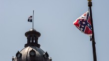 The South Carolina and American flags fly at half mast as the Confederate flag unfurls below at the Confederate Monument June 18, 2015 in Columbia, South Carolina. Legislators gathered Thursday morning to honor their co-worker Clementa Pinckney and the eight others killed Wednesday at Emanuel AME Church in Charleston, South Carolina. 