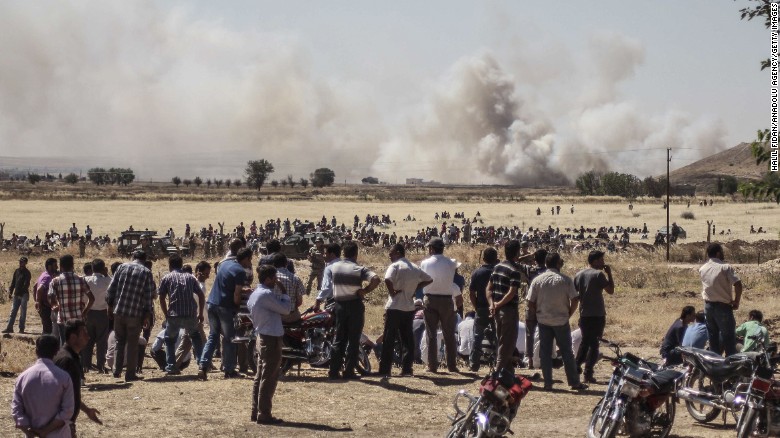 Syrians wait near the Turkish border during clashes between ISIS and Kurdish armed groups in Kobani, Syria, on Thursday, June 25. The photo was taken in Sanliurfa, Turkey. ISIS militants disguised as Kurdish security forces infiltrated Kobani on Thursday and killed &quot;many civilians,&quot; said a spokesman for the Kurds in Kobani.