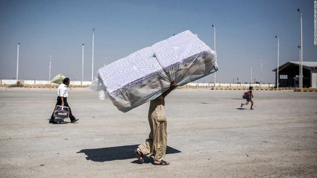 A refugee carries mattresses as he re-enters Syria from Turkey on June 22, 2015, after Kurdish People&#39;s Protection Units regained control of the area around Tal Abyad, Syria, from ISIS.