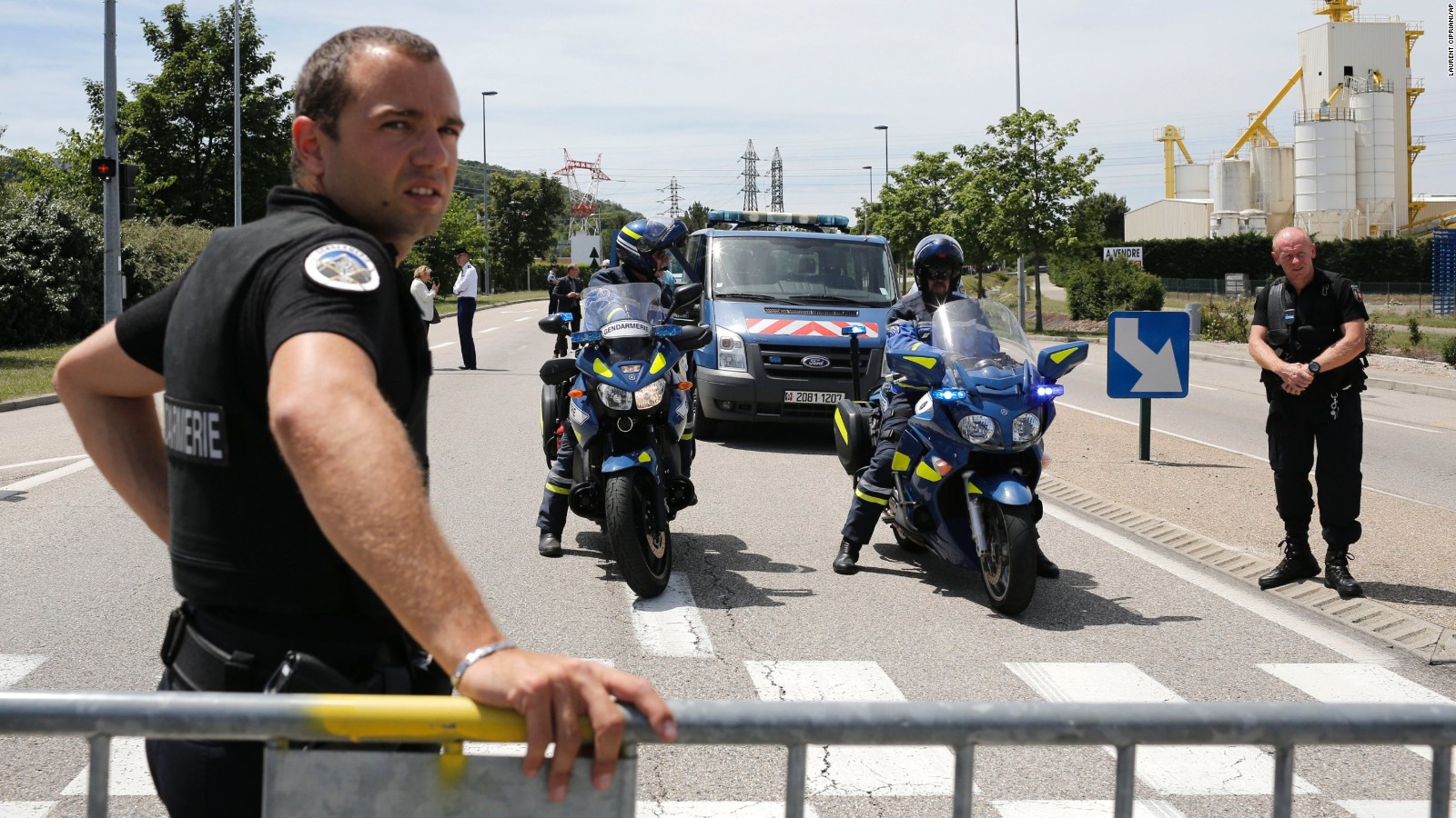 Police officer block the area where an attack took place, Friday, June 26, 2015 in Saint-Quentin-Fallavier, southeast of Lyon, France. An attacker with suspected ties to French Islamic radicals rammed a car into a gas factory Friday in southeastern France, and a severed head was staked on a post at the entrance, officials said. France immediately opened a terrorism investigation. (AP Photo/Laurent Cipriani)