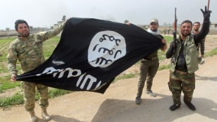 Members of Iraqi paramilitary Popular Mobilisation units, which are dominated by Shiite militias, celebrate with a flag of the Islamic State (IS) group after retaking the village of Albu Ajil, near the city of Tikrit, from the jihadist group, on March 9, 2015.