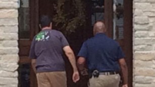 Subway pitchman Jared Fogle, left, walks back into his Zionsville, Indiana, home as investigators searched it Tuesday morning.