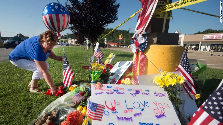 A woman places a balloon and flowers at a makeshift memorial outside the military recruiting center on Friday, July 17.