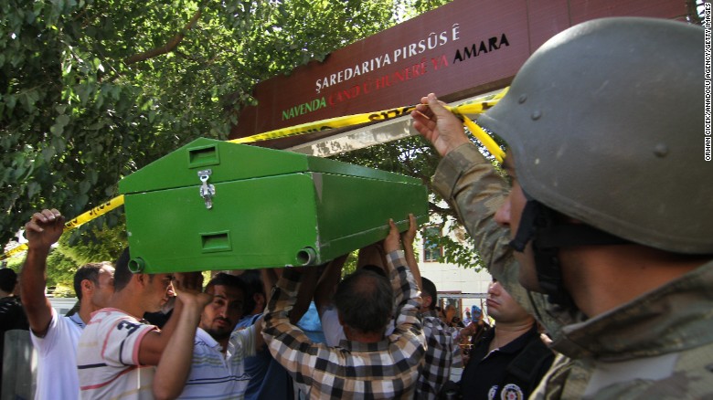 Men carry bodies away from the scene July 20. 