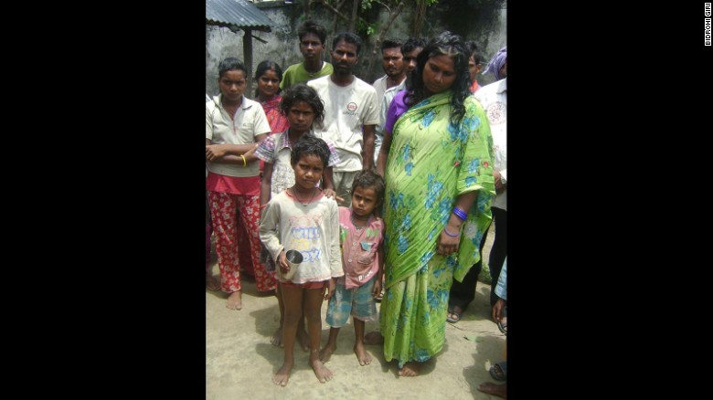 Jivan's mother dressed in green, stands with family members. According to testimony given to police, her son was lured away from their village with the promise of biscuits and the equivalent of 49 cents.