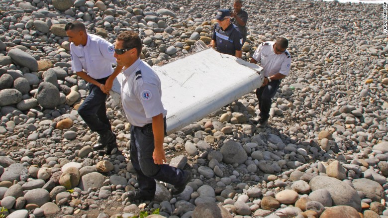 French police officers carry the plane debris on Wednesday, July 29. Experts say the metallic object may be a piece of a moving wing surface, known as a flaperon, from a Boeing 777.