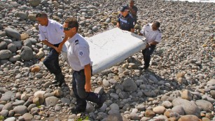 Police carry a piece of debris on Reunion Island, a French territory in the Indian Ocean, on Wednesday, July 29. A week later, authorities confirmed that the debris was from Malaysia Airlines Flight 370, which disappeared on March 8, 2014.