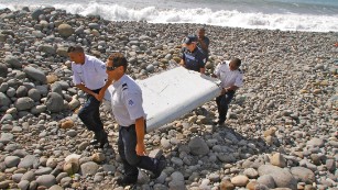 In this photo dated Wednesday, July 29, 2015, French police officers carry a piece of debris from a plane in Saint-Andre, Reunion Island. Air safety investigators, one of them a Boeing investigator, have identified the component as a "flaperon" from the trailing edge of a Boeing 777 wing, a U.S. official said. Flight 370, which disappeared March 8, 2014, with 239 people on board, is the only 777 known to be missing. (AP Photo/Lucas Marie)