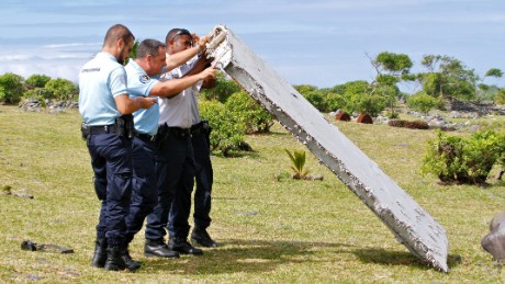 In this photo dated Wednesday, July 29, 2015, French police officers inspect a piece of debris from a plane in Saint-Andre, Reunion Island. Air safety investigators, one of them a Boeing investigator, have identified the component as a &quot;flaperon&quot; from the trailing edge of a Boeing 777 wing, a U.S. official said. Flight 370, which disappeared March 8, 2014, with 239 people on board, is the only 777 known to be missing. (AP Photo/Lucas Marie)