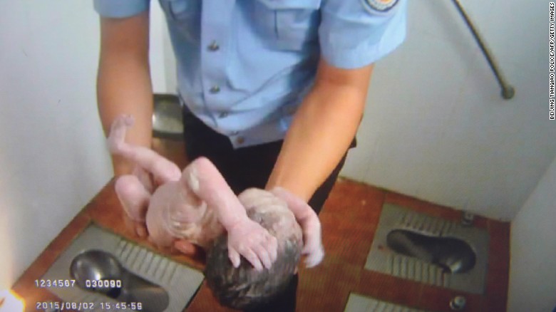 An image supplied by Beijing Tianqiao Police shows an officer holding the baby at the toilet on August 2, 2015.