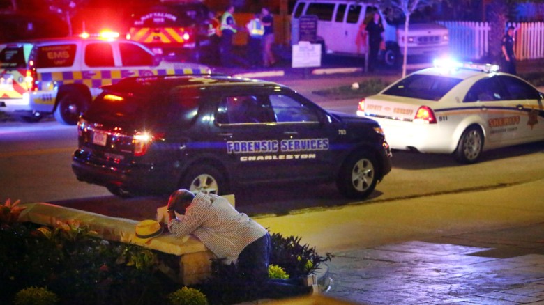 A man kneels across the street from where police gather outside the Emanuel AME Church following a shooting Wednesday, June 17, 2015, in Charleston, S.C. (Wade Spees/The Post And Courier via AP)