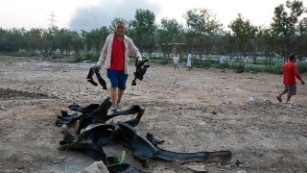 A man gathers burnt metal pieces that residents say flew from a nearby explosion in Tianjin.