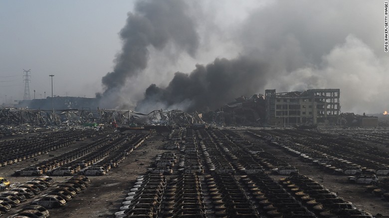 Smoke billows behind rows of burnt out cars at the site of a series of explosions in Tianjin, northern China.