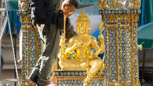 Police investigators work near the statue of Phra Phrom, the Thai interpretation of the Hindu god Brahma, at the Erawan Shrine the morning after an explosion in Bangkok, Thailand, on Tuesday, August 18. 