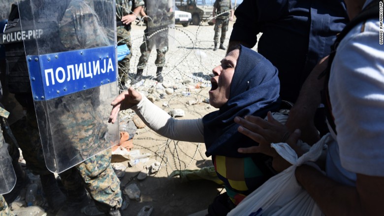 A migrant shouts at Macedonian police officers while trying to cross Greece&#39;s northern border into Macedonia. About 1,500 migrants were waiting to cross the border.