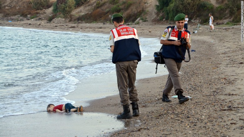 Authorities stand near Aylan&#39;s lifeless body on Wednesday, September 2. This photo went viral around the world, often with a Turkish hashtag that means &quot;Flotsam of Humanity.&quot;