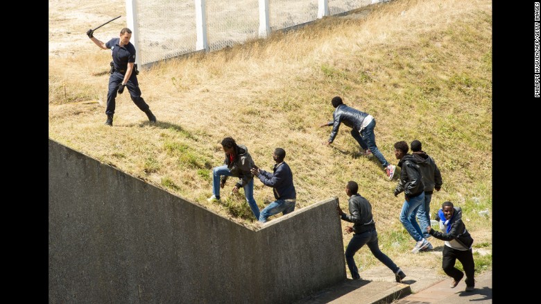 A French police officer tries to prevent migrants from heading for the Channel Tunnel to England in the northern French city of Calais on June 17.