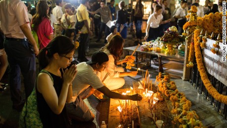 People place incense and candles and pour water at the base of the Erawan Shrine on August 24 to remember the bombing victims.