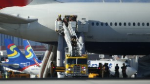 Firefighters stand outside the door of the British Airways plane that caught fire at McCarran International Airport in Las Vegas.