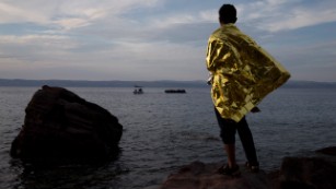 A refugee wrapped in a blanket watches a dinghy full of migrants approach the Greek island of Lesbos on Wednesday, September 9. More than 300,000 refugees and migrants heading to Europe have crossed the Mediterranean Sea so far in 2015, a U.N. spokeswoman says. Click through to see images from the refugee crisis in Europe.