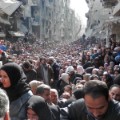 DAMASCUS, SYRIA - JANUARY 31:  In this handout provided by the United Nation Relief and Works Agency (UNRWA), Residents wait in line to receive food aid distributed in the Yarmouk refugee camp on January 31, 2014 in Damascus, Syria. The United Nations renewed calls for the Syria regime and rebels to allow food and medical aid into the Palestinian camp of Yarmouk. An estimated 18,000 people are besieged inside the camp as the conflict in Syria continues.  (Photo by United Nation Relief and Works Agency via Getty Images)