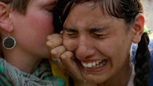 HORGOS, SERBIA - SEPTEMBER 16:  A migrant girl is overcome by pepper spray and tear gas after Hungarian police repelled an attempt by migrants to break the border post gate and pull down the razor wire fence on September 16, 2015 in Horgos, Serbia. Hungary has introduced tough new laws to administer the influx of migrants and has declared a state of emergency in two of it's counties close to the border. The new laws have created a dead end for migrants arriving at the Horgos frontier post, resulting in clashes with migrants and Hungarian police.  (Photo by Christopher Furlong/Getty Images)