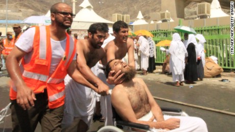 Saudi emergency personnel and Hajj pilgrims push a wounded person in a wheelchair at the site where at least 450 were killed and hundreds wounded in a stampede in Mina, near the holy city of Mecca, at the annual hajj in Saudi Arabia on September 24, 2015. The stampede, the second deadly accident to strike the pilgrims this year, broke out during the symbolic stoning of the devil ritual, the Saudi civil defence service said. 