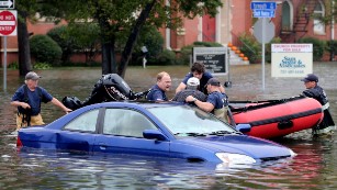 Members of Norfolk Fire-Rescue pull a man from his car in Norfolk, Virginia, on Sunday, October 4.