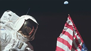 AS17-134-20384 (7-19 Dec. 1972) --- Scientist-astronaut Harrison H. Schmitt, lunar module pilot, is photographed next to the deployed United States flag during lunar surface extravehicular activity (EVA) at the Taurus-Littrow landing site. The highest part of the flag appears to point toward our planet Earth in the distant background. This picture was taken by astronaut Eugene A. Cernan, Apollo 17 commander. While astronauts Cernan and Schmitt descended in the Lunar Module (LM) to explore the moon, astronaut Ronald E. Evans, command module pilot, remained with the Command and Service Modules (CSM) in lunar orbit.