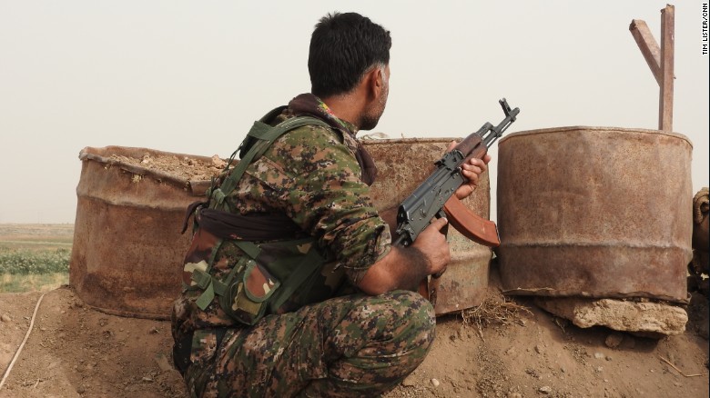 A soldier with the Kurdish YPG looks out over the front line in the fight against ISIS