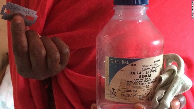 A Kenyan "cutter" (Female Genital Mutilation practitioner) holds up the razor blades and ethanol spirit used FGM. 