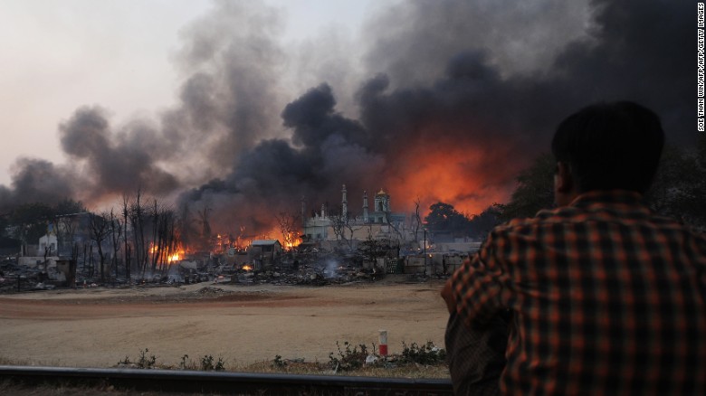 A resident watches as black smoke rises from burning houses in riot-hit Meiktila, central Myanmar on March 21, 2013. At least 10 people were killed in riots in central Myanmar.