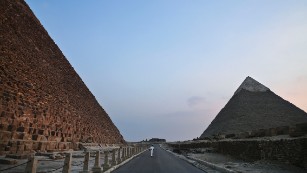 An Egyptian policeman walks past the Khufu pyramid, left, towards the Khafre pyramid in Giza, Egypt. Egypt's Antiquities Ministry says a scanning project in the Giza pyramids has identified thermal anomalies, including one in the largest pyramid, built by Cheops, known locally as Khufu.