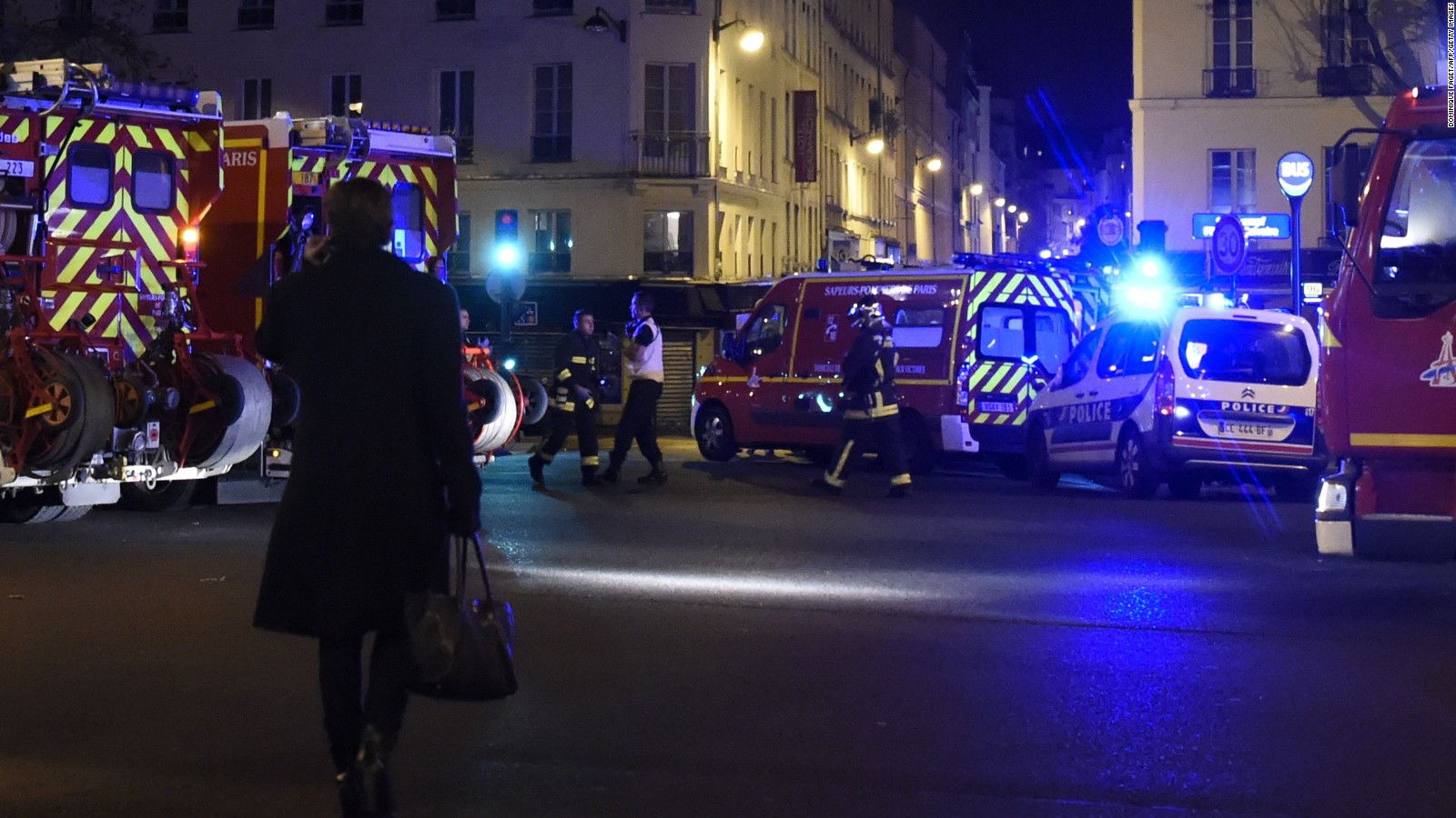 A woman walks past police and fighter fighters following an attack in the Oberkampf area of Paris on November 13, 2015. A number of people were killed and others injured in a series of gun attacks across Paris, as well as explosions outside the national stadium where France was hosting Germany. AFP PHOTO / DOMINIQUE FAGETDOMINIQUE FAGET/AFP/Getty Images