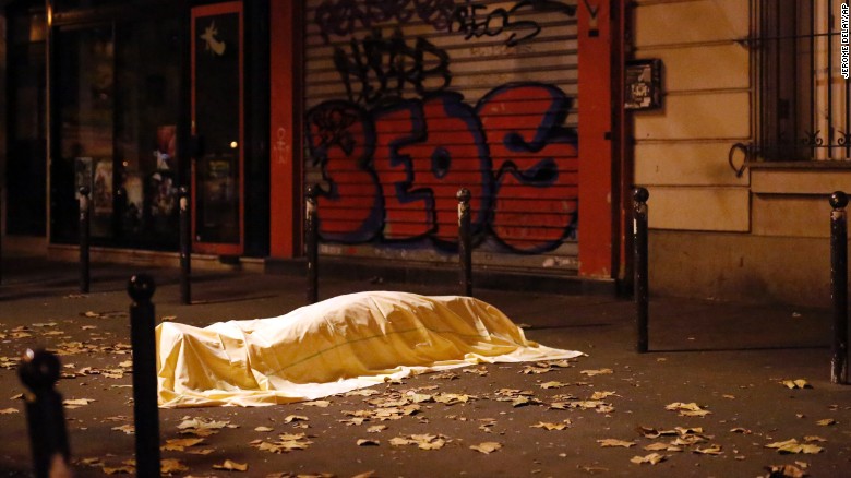 A body, covered by a sheet, is seen on the sidewalk outside the Bataclan theater.