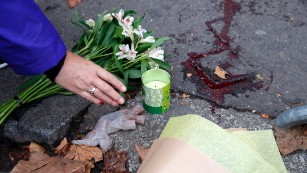 A woman places a candle outside the Bataclan concert hall, Saturday, Nov. 14, 2015 in Paris. French President Francois Hollande said more than 120 people died Friday night in shootings at Paris cafes, suicide bombings near France's national stadium and a hostage-taking slaughter inside a concert hall. (AP Photo/Christophe Ena)